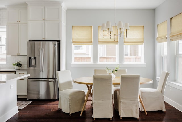 dining space featuring an inviting chandelier, a healthy amount of sunlight, and dark wood-type flooring