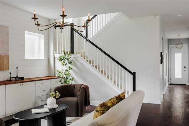 entryway with an inviting chandelier and dark wood-type flooring