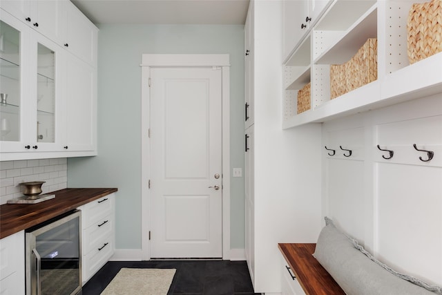 mudroom featuring beverage cooler and dark tile patterned flooring