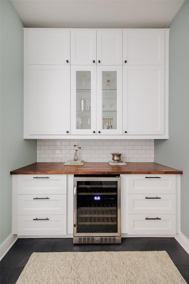 bar with wine cooler, dark tile patterned flooring, decorative backsplash, white cabinets, and butcher block counters