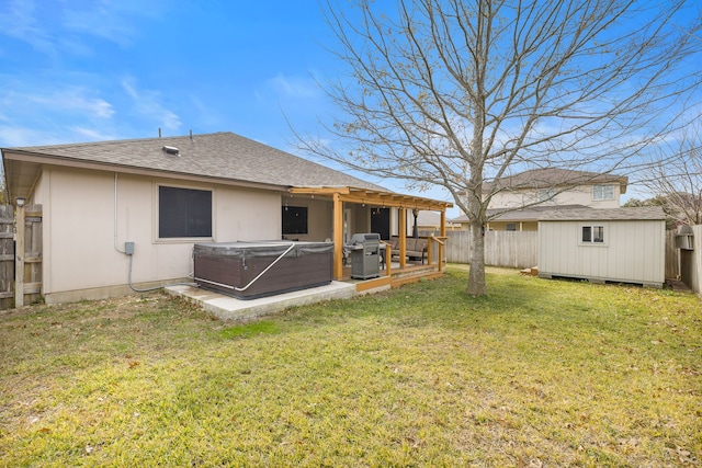 back of property with a yard, a hot tub, and a storage unit