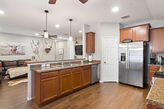 kitchen with sink, appliances with stainless steel finishes, kitchen peninsula, pendant lighting, and dark wood-type flooring