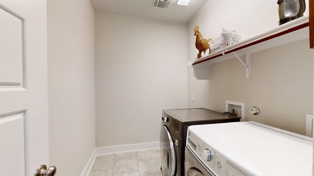 clothes washing area featuring light tile patterned flooring and washer and clothes dryer