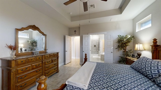 tiled bedroom with ceiling fan, ensuite bathroom, and a tray ceiling