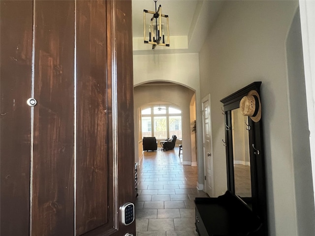 hallway featuring tile patterned flooring, a towering ceiling, and a chandelier