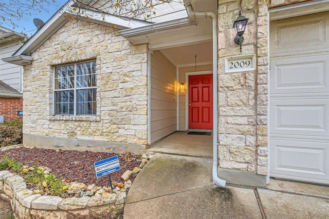 entrance to property with a garage and stone siding