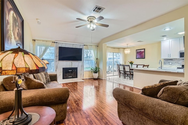 living room with a fireplace, recessed lighting, visible vents, ceiling fan, and wood finished floors