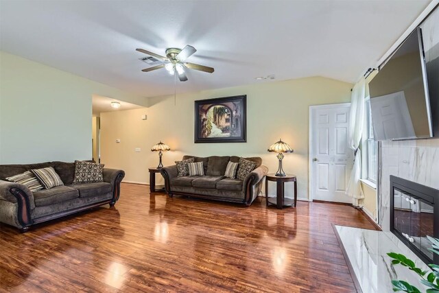 living room featuring ceiling fan, dark hardwood / wood-style flooring, lofted ceiling, and a fireplace