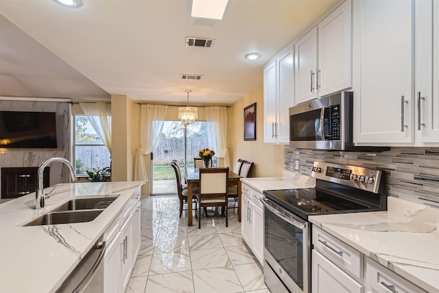 kitchen with visible vents, stainless steel appliances, white cabinetry, pendant lighting, and a sink