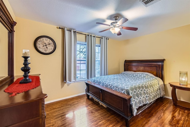 bedroom featuring a textured ceiling, dark wood-style flooring, visible vents, and baseboards