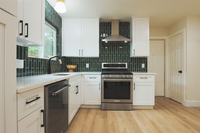 kitchen with dishwasher, sink, white cabinets, stainless steel range, and wall chimney range hood