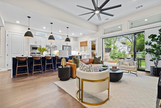 living room featuring ceiling fan, light hardwood / wood-style floors, and sink