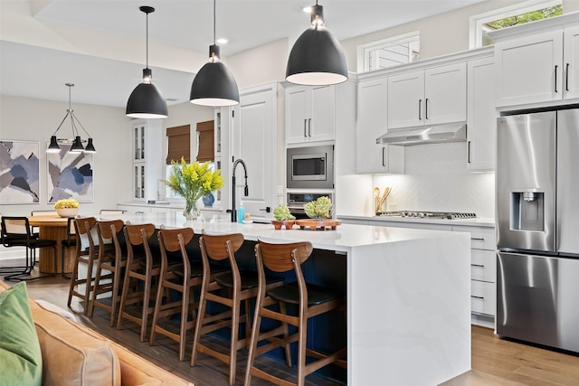 kitchen featuring stainless steel appliances, white cabinets, a breakfast bar, and a spacious island