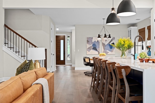 interior space with sink, decorative light fixtures, a kitchen bar, and dark hardwood / wood-style floors