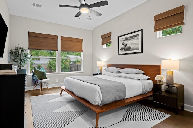 bedroom featuring dark hardwood / wood-style flooring, multiple windows, and ceiling fan