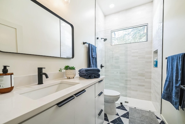 bathroom with tile patterned flooring, a tile shower, vanity, and toilet