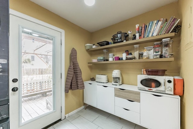 clothes washing area featuring washer and dryer, laundry area, light tile patterned flooring, and baseboards