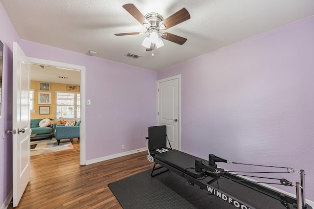 exercise room with dark wood-type flooring and ceiling fan