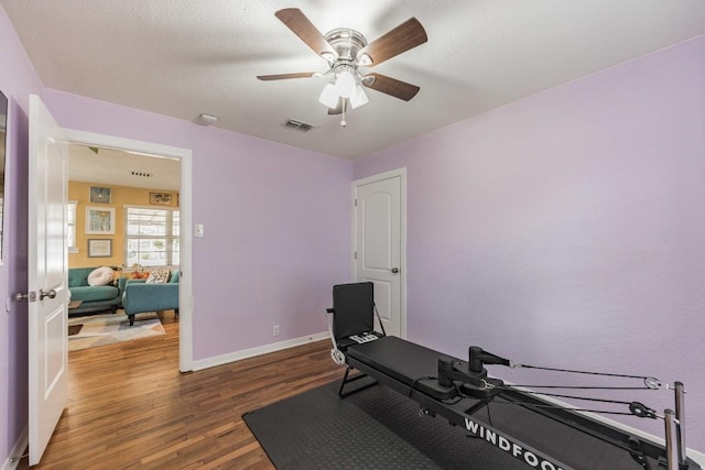 workout room with visible vents, baseboards, ceiling fan, and wood finished floors