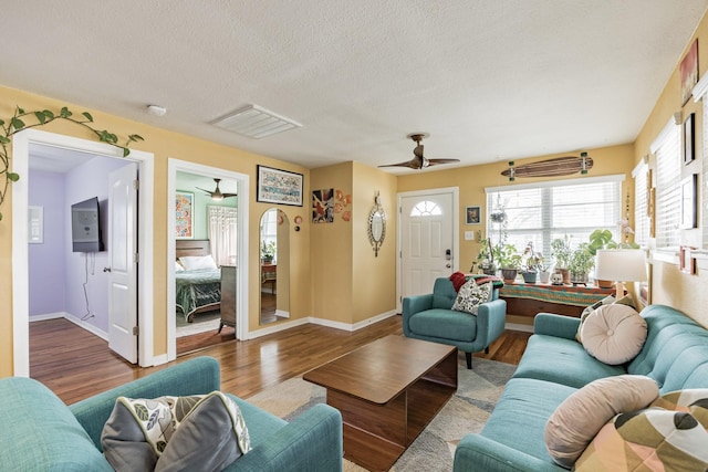 living room featuring hardwood / wood-style flooring, a textured ceiling, and ceiling fan