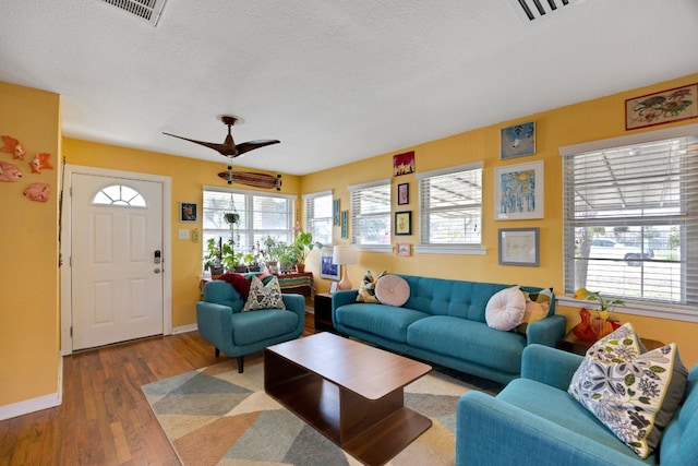 living room featuring a textured ceiling, wood finished floors, visible vents, and ceiling fan