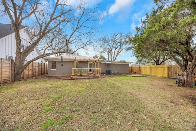405 W 17th St, Georgetown, TX 78626 - back of property featuring a fenced backyard, a deck, brick siding, and a lawn