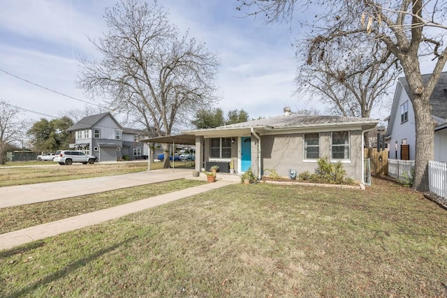 view of front of property with an attached carport, fence, concrete driveway, a front yard, and metal roof