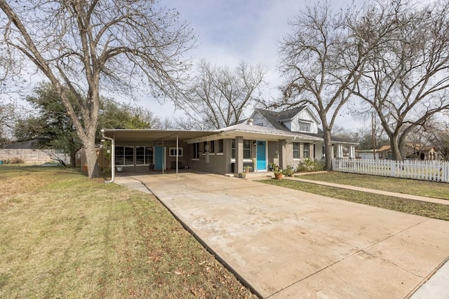 view of front facade with fence, concrete driveway, a front yard, stucco siding, and a carport