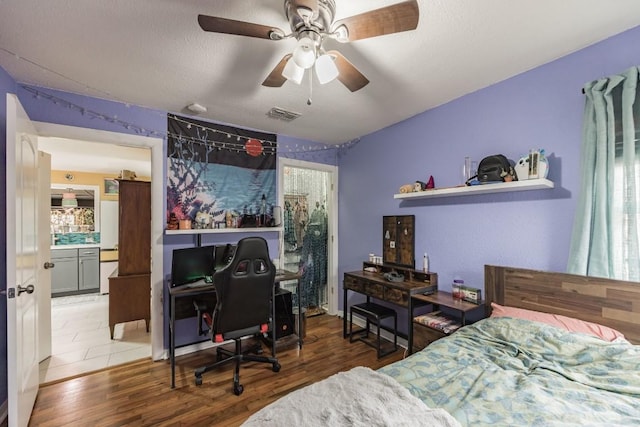 bedroom featuring a textured ceiling, wood finished floors, visible vents, and ceiling fan