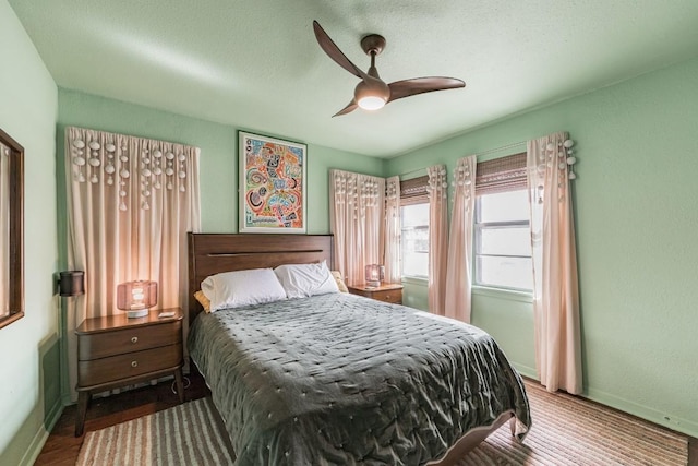 bedroom featuring baseboards, wood finished floors, and a ceiling fan