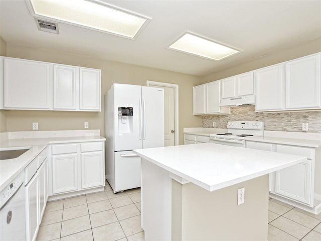 kitchen featuring white appliances, a center island, light tile patterned floors, decorative backsplash, and white cabinets