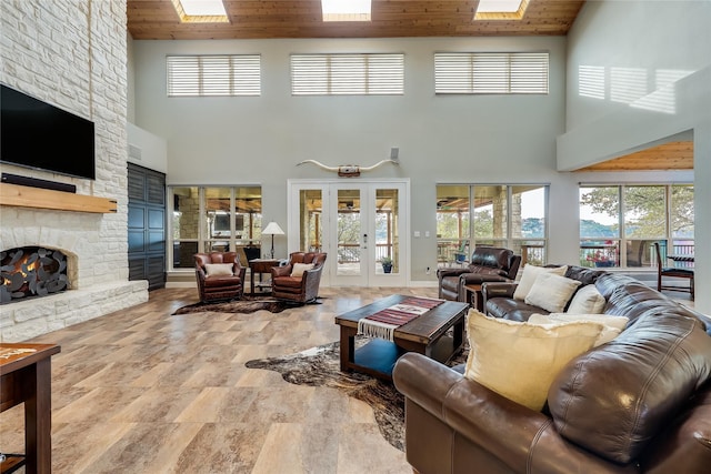 living room with a towering ceiling, french doors, a stone fireplace, and wood ceiling