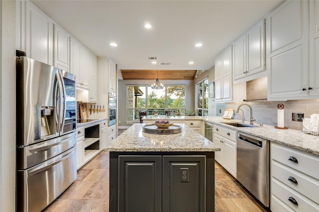 kitchen with pendant lighting, a center island, sink, stainless steel appliances, and light stone counters