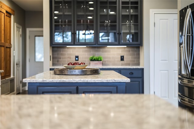 bar featuring decorative backsplash, blue cabinets, and stainless steel refrigerator