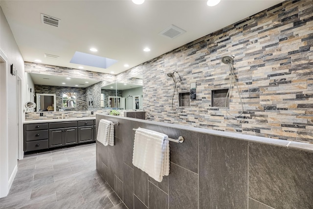 bathroom with a shower, vanity, and a skylight