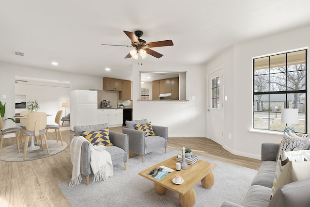 living room featuring ceiling fan, light hardwood / wood-style floors, and plenty of natural light