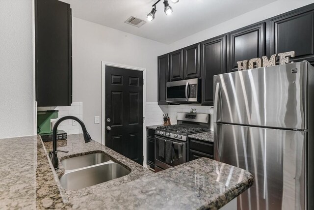 kitchen featuring light stone countertops, stainless steel appliances, backsplash, and sink