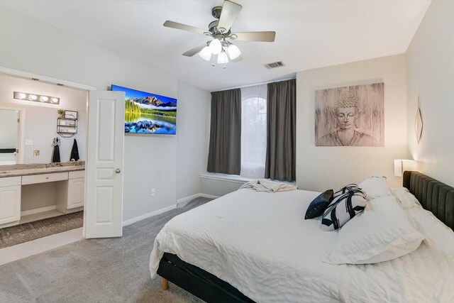 bedroom with ceiling fan, light carpet, and connected bathroom