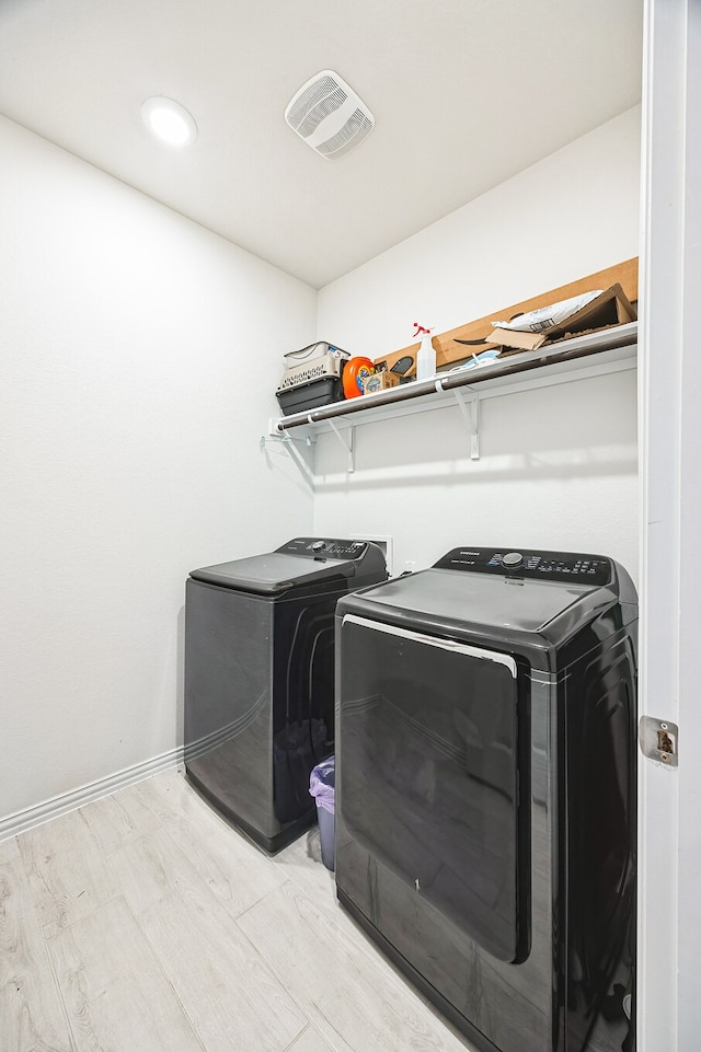 clothes washing area featuring separate washer and dryer and light hardwood / wood-style flooring