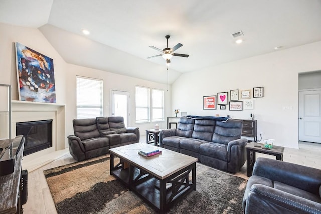 317 Barley Fork Ln, Hutto, TX 78634 - living area with a glass covered fireplace, ceiling fan, wood finished floors, and vaulted ceiling