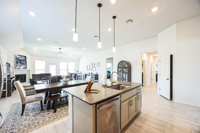 kitchen with lofted ceiling, sink, dishwasher, hanging light fixtures, and a center island with sink