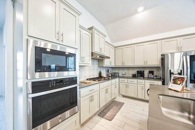 kitchen featuring sink, tasteful backsplash, vaulted ceiling, and appliances with stainless steel finishes