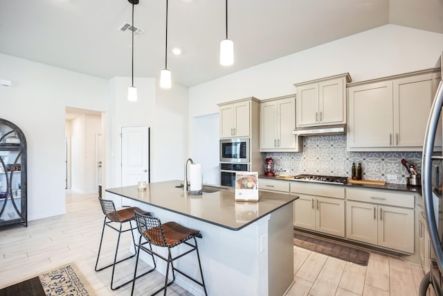 kitchen featuring sink, stainless steel appliances, a kitchen island with sink, and pendant lighting