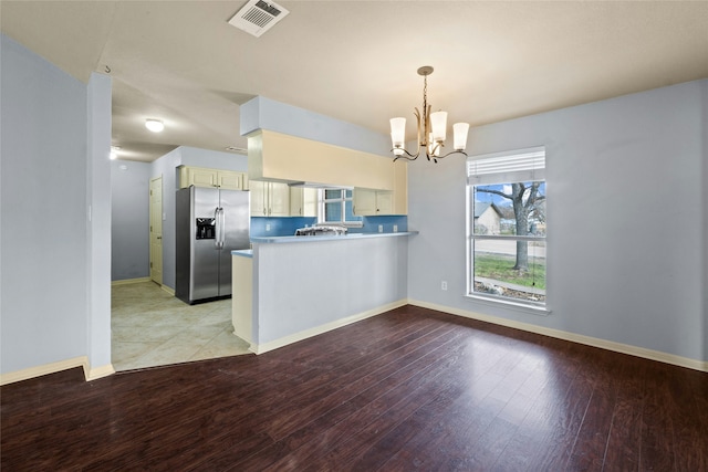 kitchen with a notable chandelier, kitchen peninsula, light hardwood / wood-style flooring, hanging light fixtures, and stainless steel fridge with ice dispenser