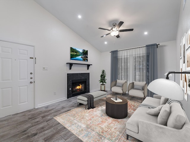 living room featuring a high end fireplace, ceiling fan, vaulted ceiling, and dark wood-type flooring