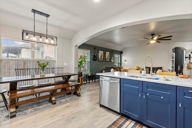 kitchen with blue cabinetry, light countertops, hanging light fixtures, a sink, and dishwasher