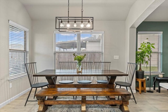 dining space featuring an inviting chandelier, vaulted ceiling, and hardwood / wood-style flooring