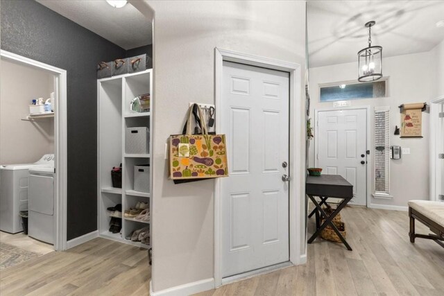 foyer featuring an inviting chandelier, light hardwood / wood-style floors, and separate washer and dryer