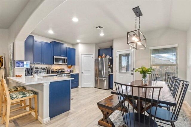 kitchen featuring blue cabinets, kitchen peninsula, appliances with stainless steel finishes, and a kitchen breakfast bar