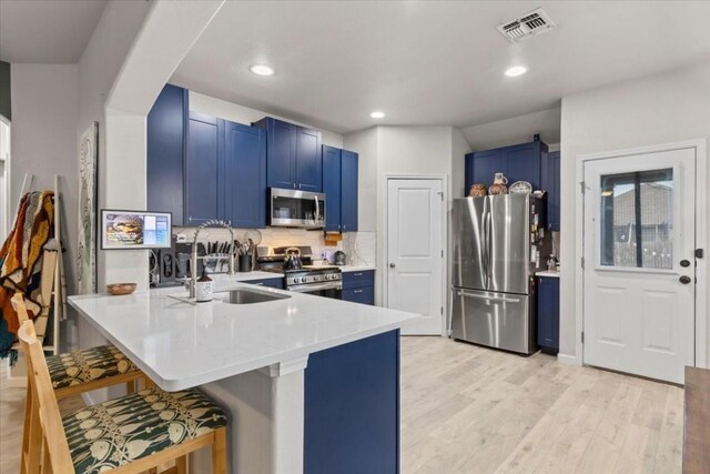 kitchen with kitchen peninsula, stainless steel appliances, blue cabinets, and a kitchen bar